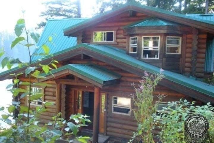 Classic Green-Roof Log Cabin Tucked Among Tall Evergreens at Lake Cavanaugh